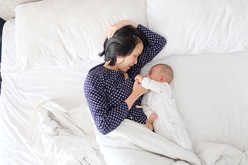 Photo of woman lying with baby. Postpartum anxiety counseling in Houston, Tx 77006
